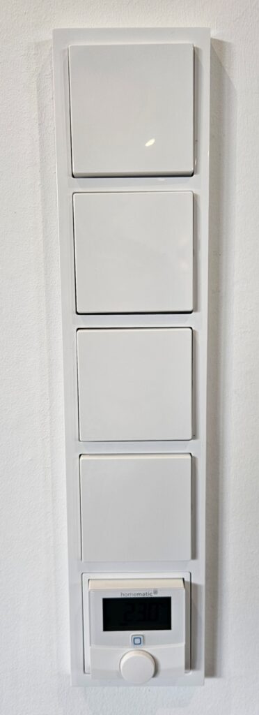 Weiße Wandtaster mit Raumthermostat zur Bedienung verschiedener Smart-Home-Funktionen